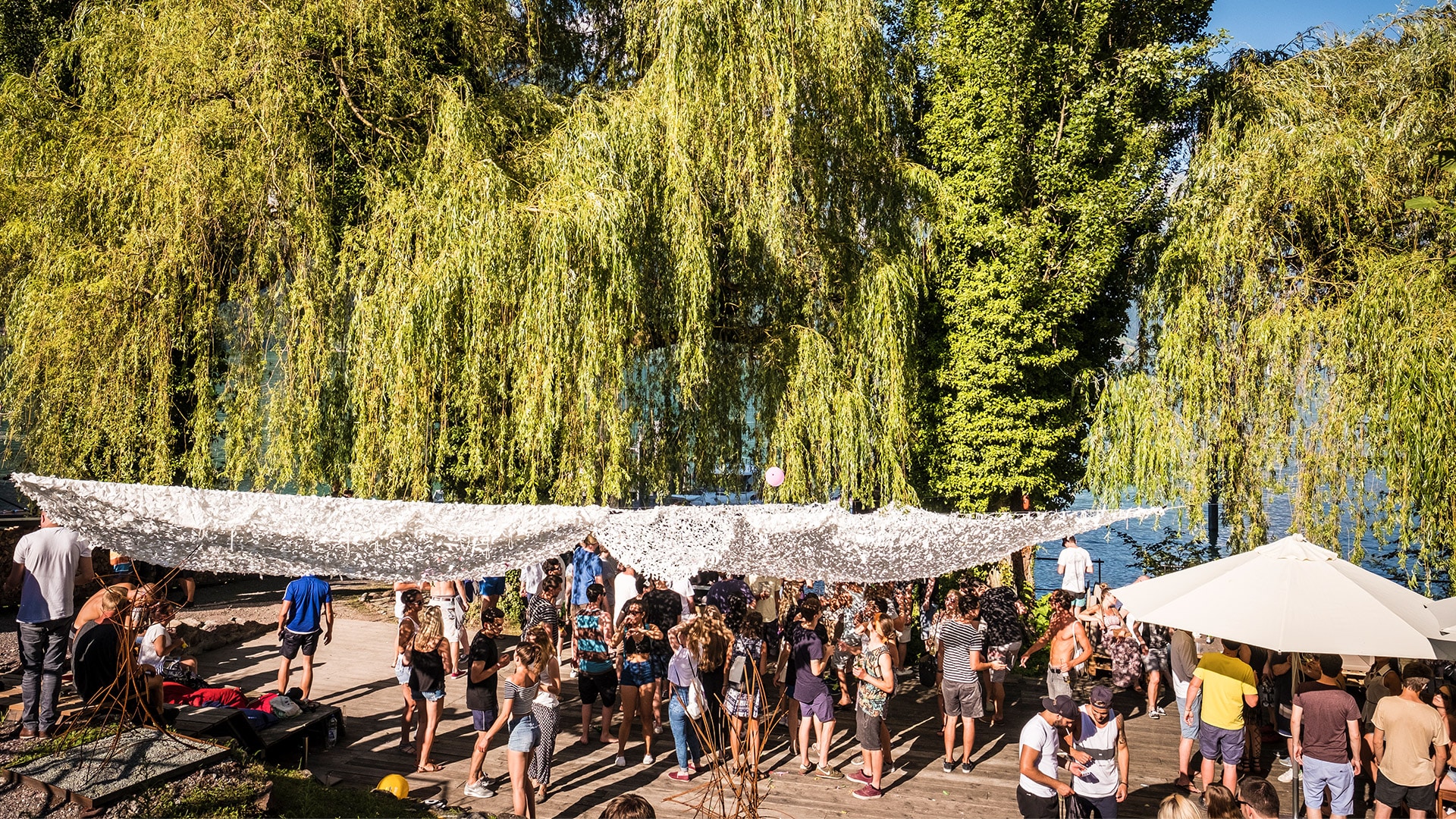 Viele junge Menschen feiern ein Fest auf dem Sagisteg umgeben von Bäumen