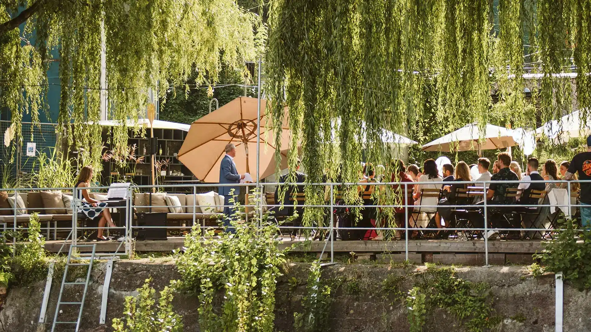 Viele junge Menschen feiern ein Fest auf dem Sagisteg umgeben von Bäumen